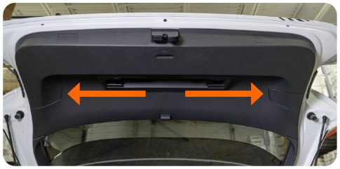 Inside of the open rear hatch of a VW Golf MK8 with arrows pointing left and right to the two tail light access covers