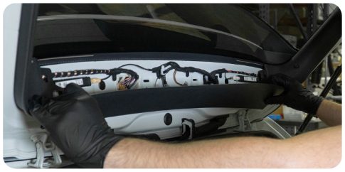 Hands pulling the middle trim piece away from the rear window of a MK8 Golf hatch