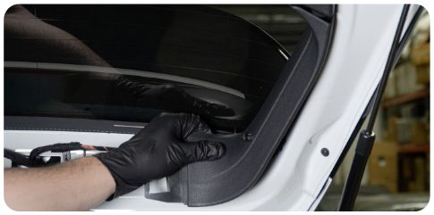 Gloved hands removing a side trim piece from the hatch of a MK8 Golf