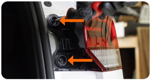 Two arrows pointing to the T25 bolts behind the outer tail light of a MK8 Golf