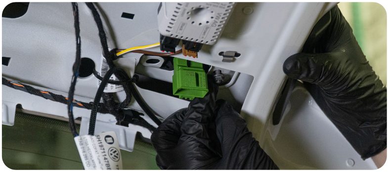 Gloved hands seating the new inner tail light on the hatch of a MK8 Golf with the connector visible through the opening