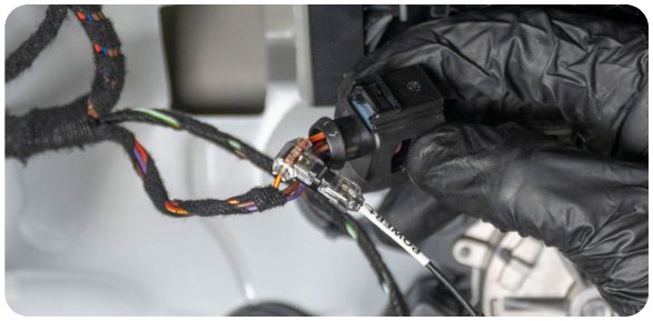Wire tap being crimped onto the red and yellow wire at the rear view camera module plug